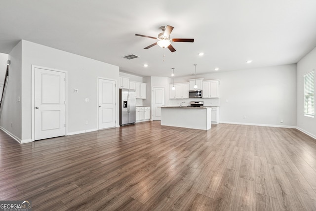 unfurnished living room featuring baseboards, visible vents, a ceiling fan, wood finished floors, and recessed lighting