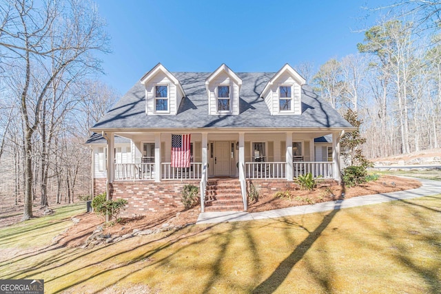 view of front of house featuring roof with shingles, a porch, and a front yard