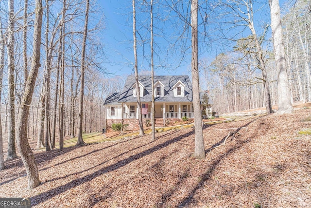 cape cod-style house featuring a porch and brick siding