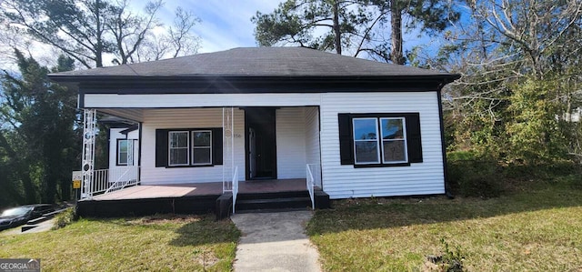 view of front of home with a porch, a front yard, and a shingled roof