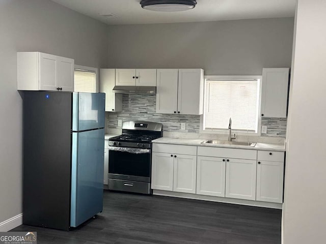 kitchen with white cabinets, decorative backsplash, stainless steel appliances, light countertops, and a sink