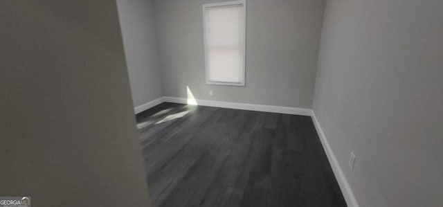 spare room with dark wood-style floors and baseboards