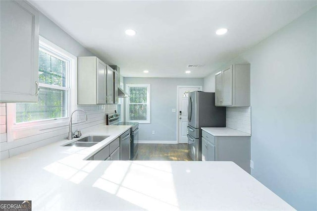 kitchen with backsplash, visible vents, appliances with stainless steel finishes, and a sink