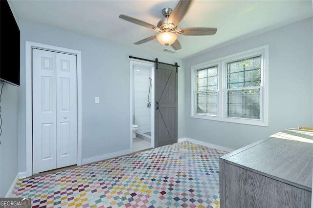 bedroom with a barn door, baseboards, visible vents, and a closet