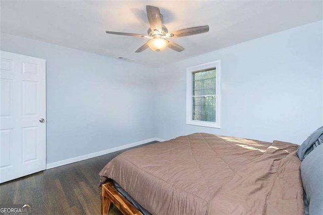 bedroom featuring a ceiling fan, wood finished floors, visible vents, and baseboards