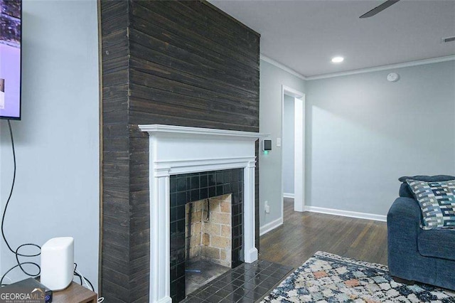 living room featuring wood finished floors, recessed lighting, crown molding, baseboards, and a tile fireplace