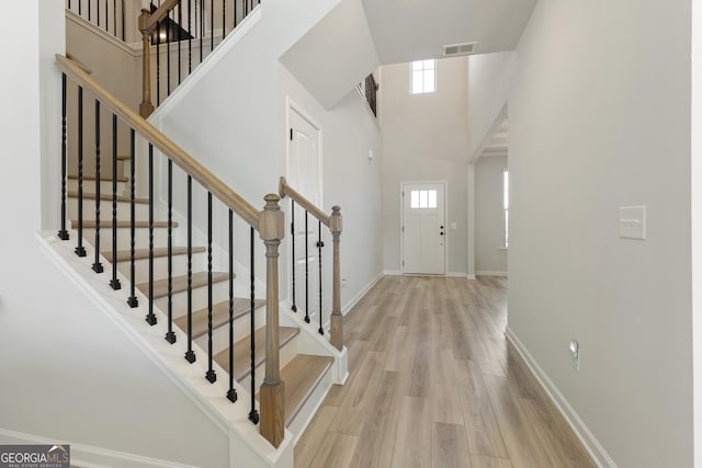 entrance foyer with baseboards, visible vents, a high ceiling, and wood finished floors