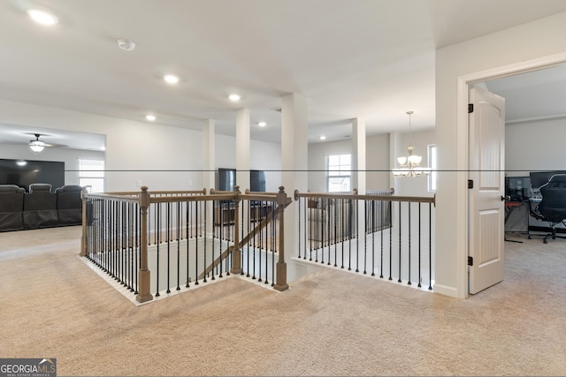 hall with a chandelier, a wealth of natural light, and carpet