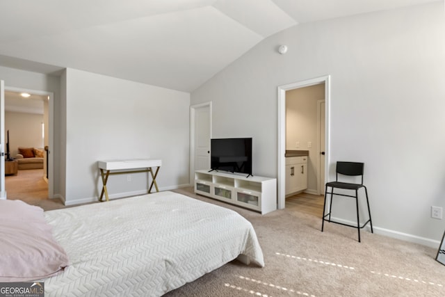 bedroom featuring lofted ceiling, baseboards, ensuite bath, and carpet