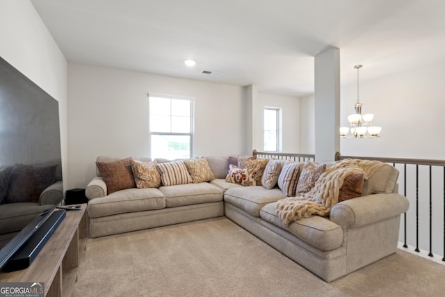 living area with light carpet, visible vents, and an inviting chandelier