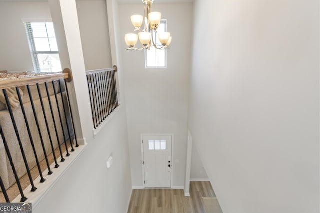 entrance foyer featuring a notable chandelier, plenty of natural light, baseboards, and wood finished floors