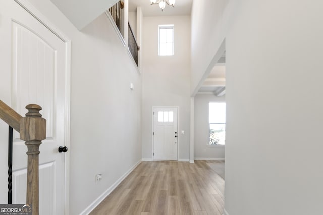 foyer featuring light wood-style flooring, a high ceiling, and baseboards