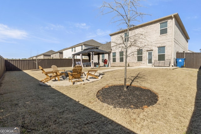 rear view of house with a gazebo, brick siding, a patio, and a fenced backyard