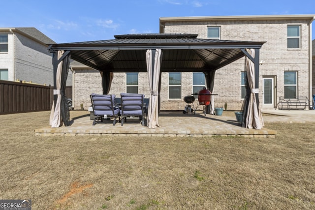 rear view of house with a patio area, a gazebo, fence, and brick siding