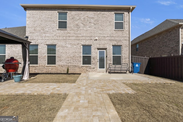 rear view of property with a patio, brick siding, and fence