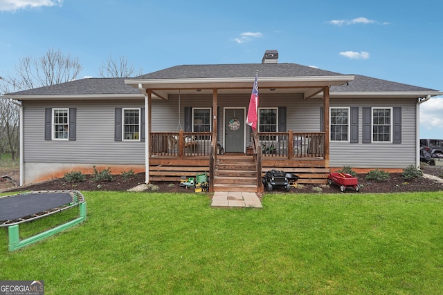 rear view of property featuring covered porch, a yard, a shingled roof, and a chimney