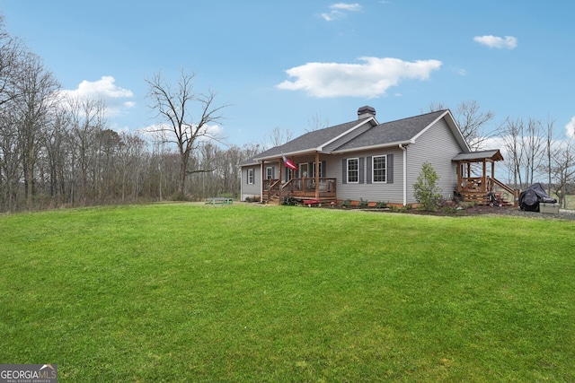 view of side of home with a chimney, a deck, a lawn, and roof with shingles