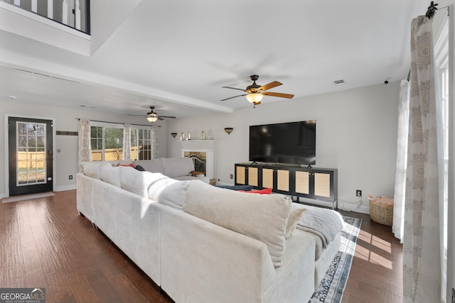 living area with a fireplace with raised hearth, visible vents, baseboards, beam ceiling, and dark wood-style floors