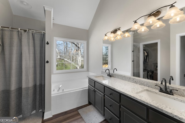 full bathroom with plenty of natural light, vaulted ceiling, and a sink