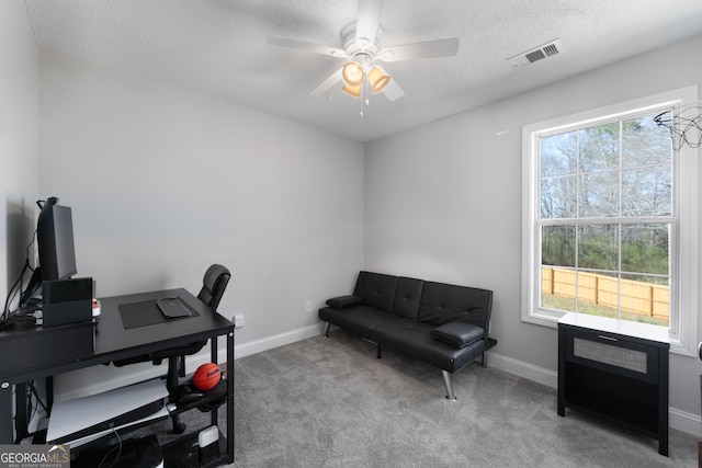 carpeted office featuring a textured ceiling, ceiling fan, visible vents, and baseboards