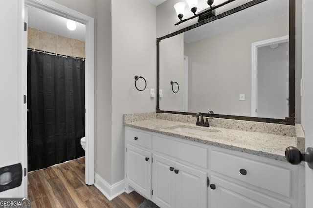 bathroom with baseboards, toilet, a shower with curtain, wood finished floors, and vanity