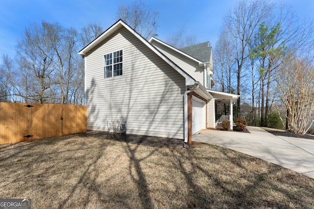 view of property exterior with a garage, a gate, fence, and concrete driveway