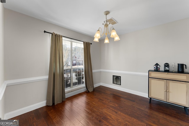 unfurnished dining area with visible vents, baseboards, dark wood-type flooring, a fireplace, and a notable chandelier