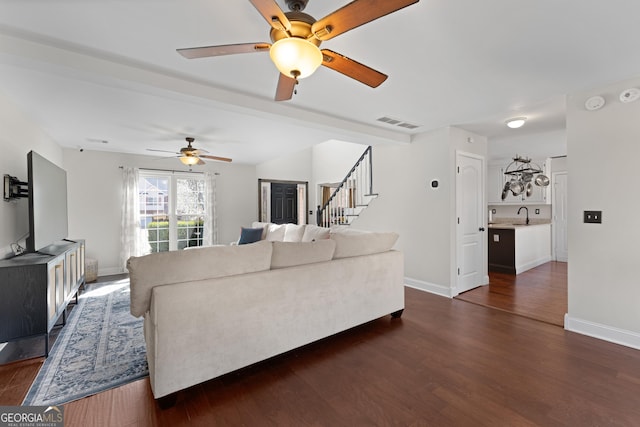 living area with dark wood-style floors, visible vents, stairway, and baseboards