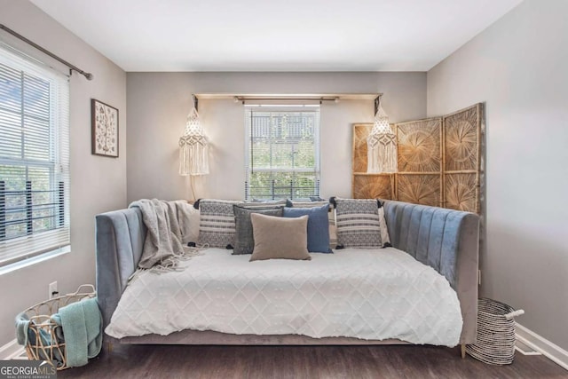 bedroom featuring multiple windows, baseboards, and wood finished floors