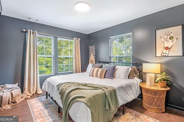 bedroom with multiple windows, visible vents, and wood finished floors