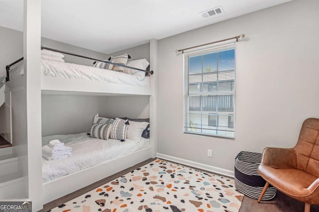 bedroom with visible vents, baseboards, and wood finished floors