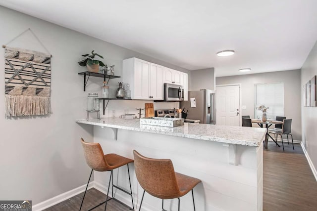 kitchen featuring stainless steel appliances, a peninsula, white cabinetry, open shelves, and dark wood finished floors