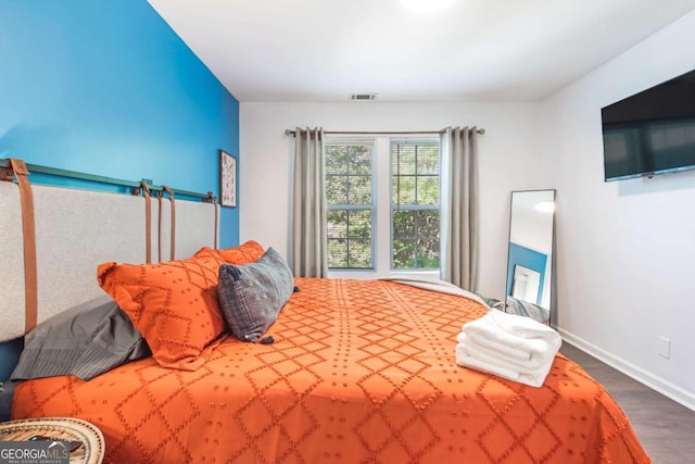 bedroom featuring wood finished floors, visible vents, and baseboards