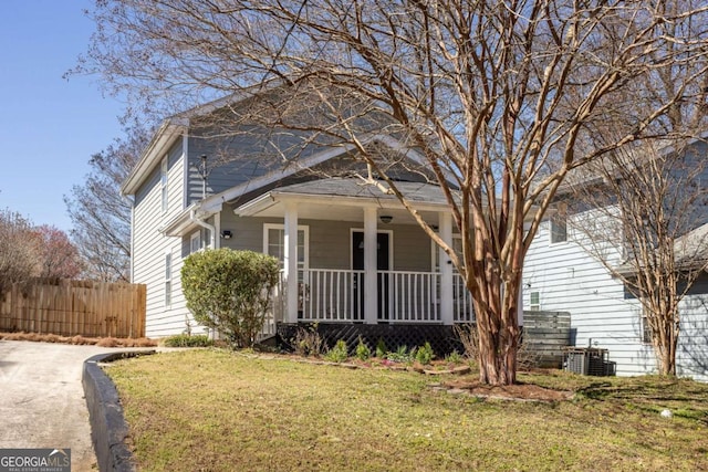 view of front facade with a front yard, covered porch, central AC, and fence