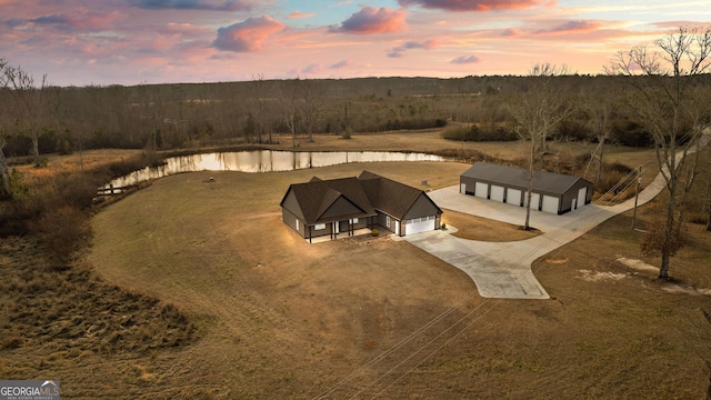 aerial view at dusk featuring a water view and a view of trees