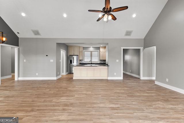 unfurnished living room featuring baseboards, visible vents, a ceiling fan, light wood-type flooring, and a sink