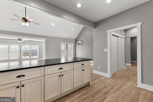 kitchen with dark countertops, light wood-style floors, vaulted ceiling, and a wealth of natural light