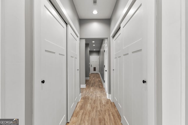 corridor featuring light wood-style flooring, visible vents, baseboards, and recessed lighting