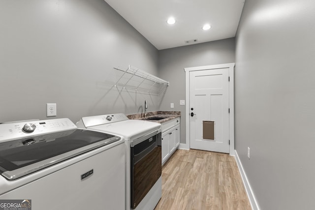 clothes washing area with cabinet space, visible vents, baseboards, light wood-style flooring, and separate washer and dryer