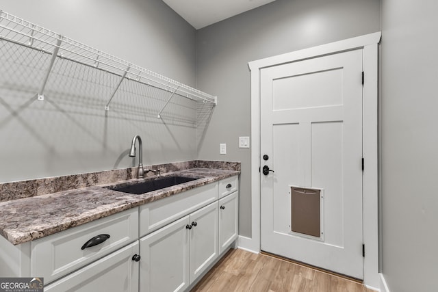 laundry room with light wood-type flooring and a sink