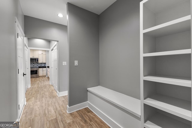 hallway with recessed lighting, baseboards, and light wood finished floors