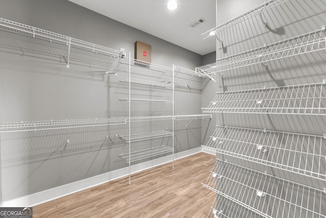 spacious closet featuring visible vents and wood finished floors