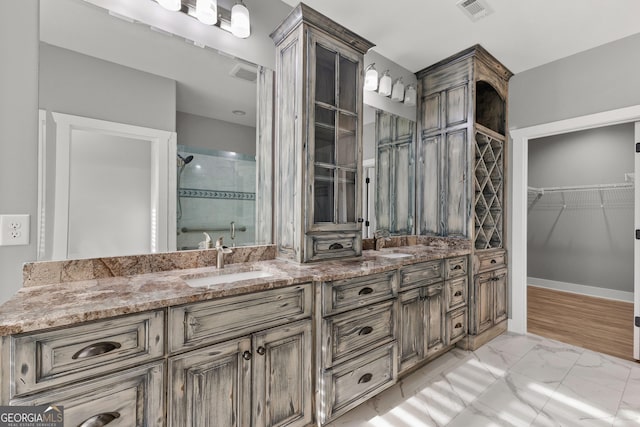 full bathroom with double vanity, a stall shower, visible vents, and a sink