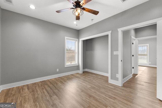 unfurnished bedroom featuring light wood-style floors, multiple windows, and baseboards