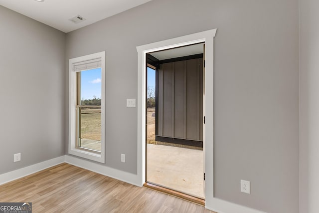 spare room featuring wood finished floors, visible vents, and baseboards