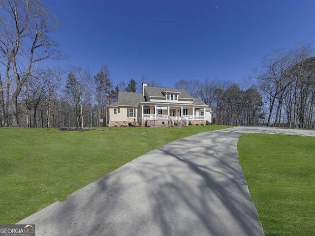 view of front of home with driveway, a porch, a front lawn, and a chimney