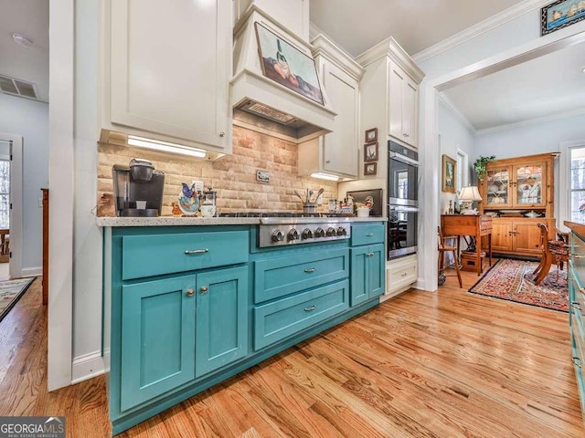 kitchen featuring visible vents, light wood finished floors, custom exhaust hood, tasteful backsplash, and crown molding