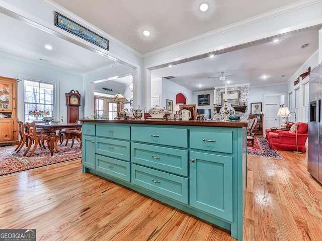 kitchen with light wood-style floors, ornamental molding, open floor plan, and a ceiling fan