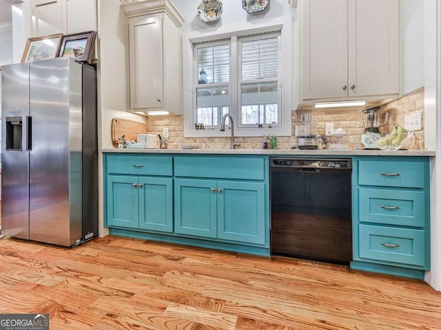 kitchen featuring dishwasher, stainless steel refrigerator with ice dispenser, a sink, and blue cabinets