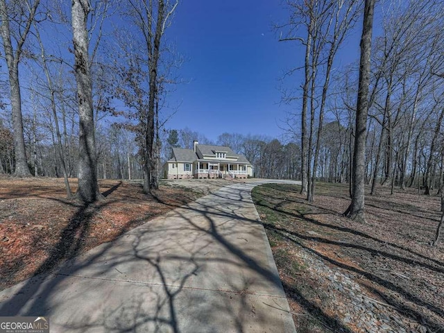 view of street with concrete driveway and a view of trees